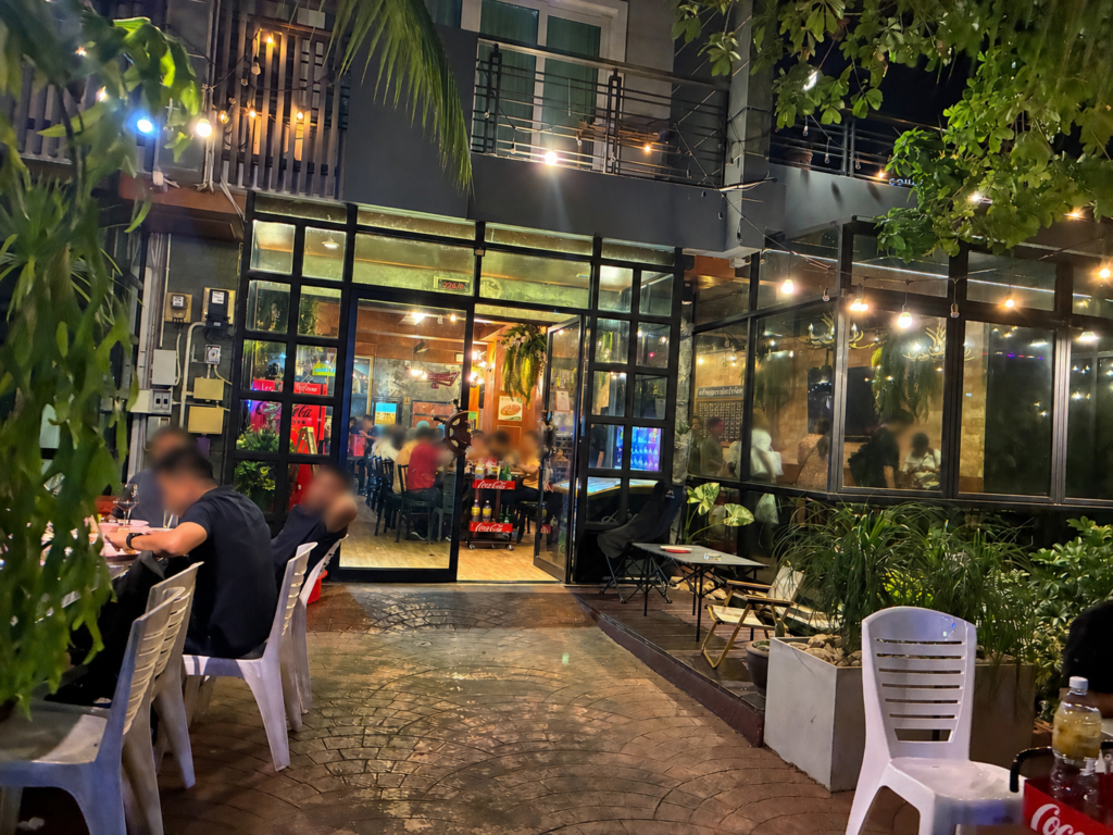 夜のKo Ang Seafoodの外観。ガラス張りの店内と緑の植物に囲まれたテラス席