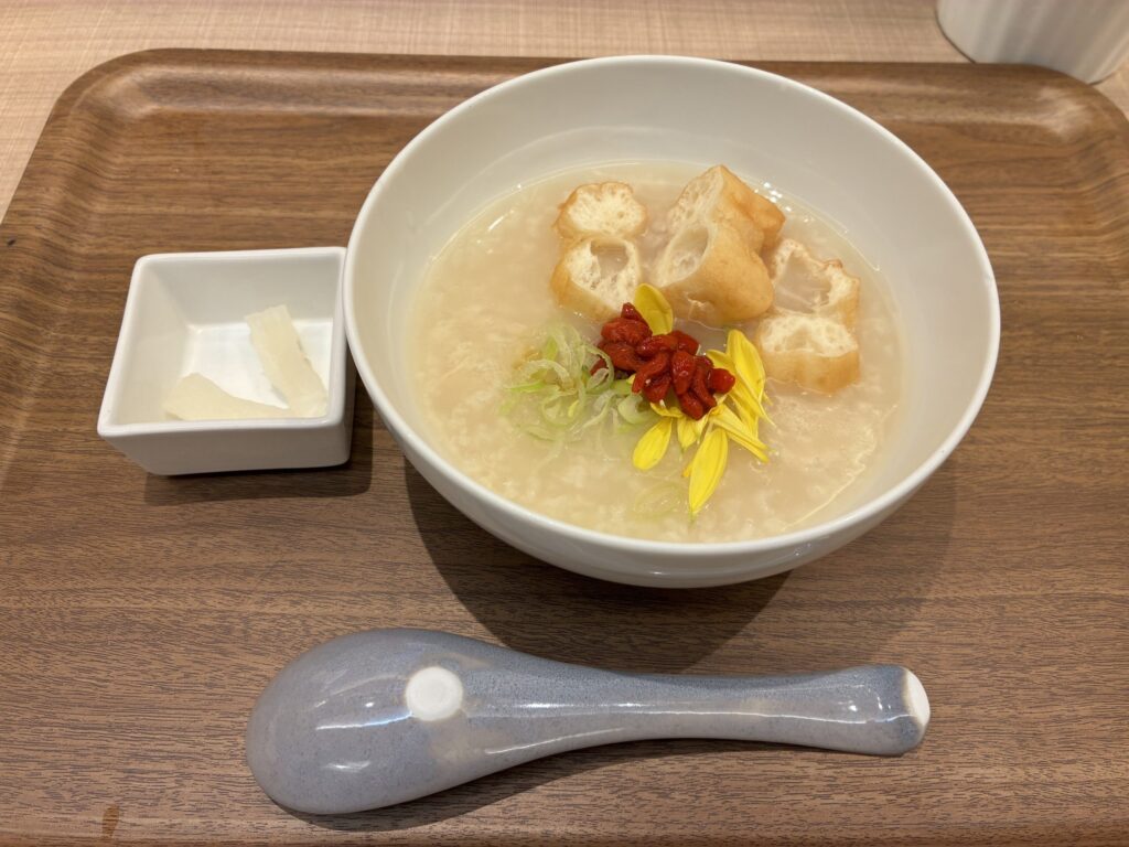 10ZENのプレーン粥。クコの実・揚げパン・食用菊がのり、漬物が添えられている