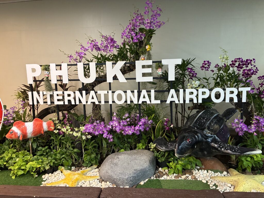 プーケット国際空港の到着ロビー。花とカメのオブジェと空港名の看板