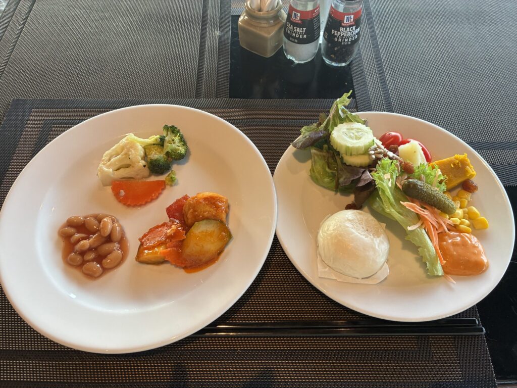 ビュッフェで盛り付けた2枚のお皿。野菜、豆、魚料理、サラダ、ポーチドエッグなど