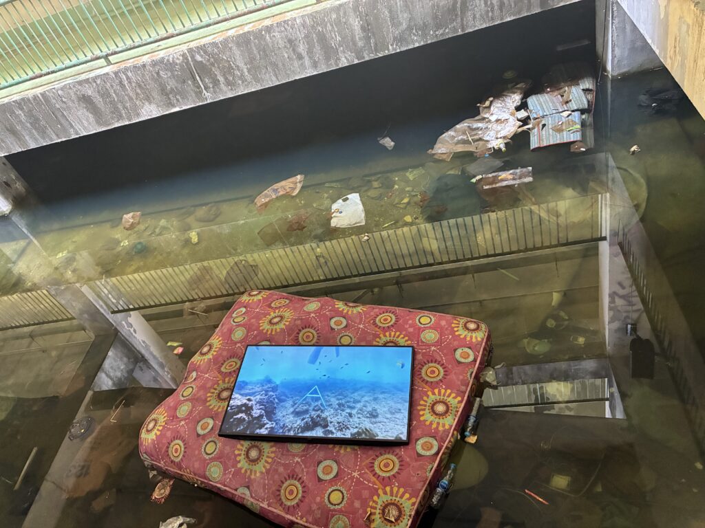 かつての生鮮市場。花柄のマットレスの上に海中の映像を映すモニターが置かれている