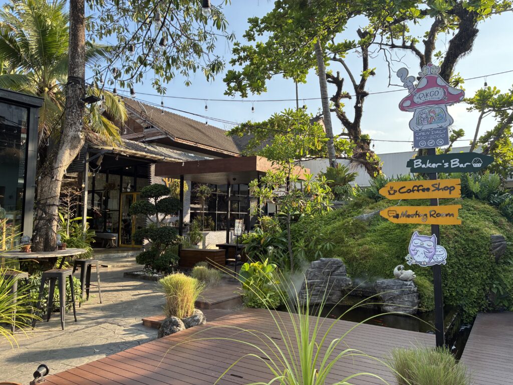 緑の植物に囲まれたPIKGO Café'の外観。Baker's Bar、Coffee Shopの案内板がある