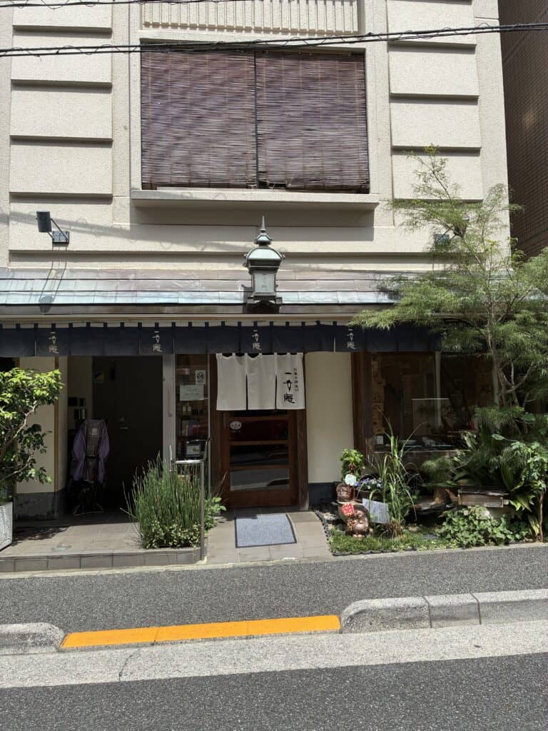 一幸庵の店構え。暖簾と季節の草花が置かれた、小石川の和菓子店の入り口