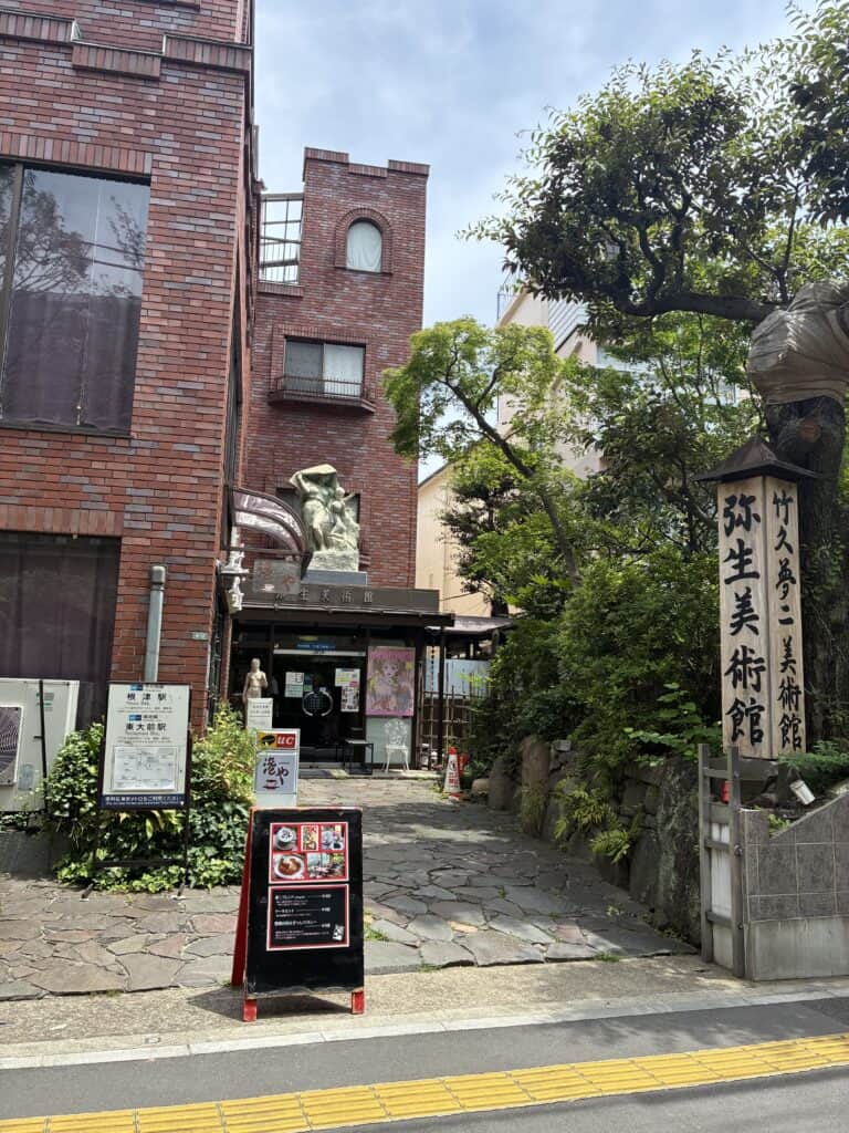 弥生美術館の外観。レンガ色の建物と、石の門標が立つ入り口