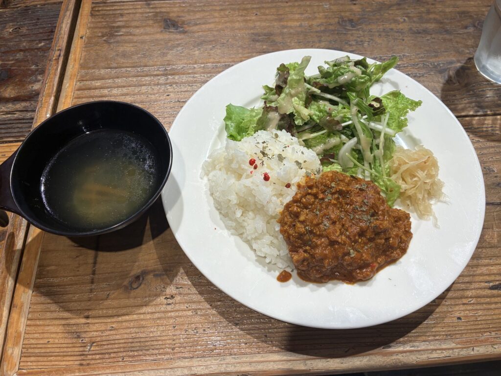 キーマカレーとコンソメスープ。白い皿にご飯、キーマ、サラダが盛られている