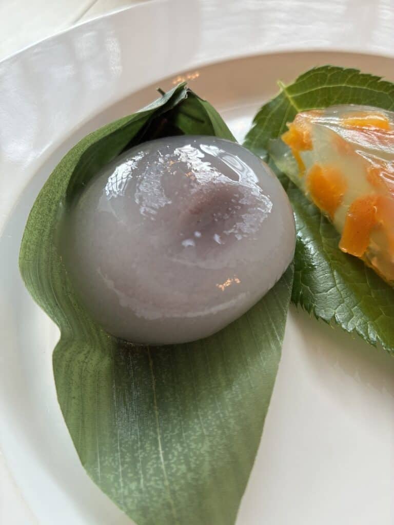 笹の葉にのった玉川屋の水まんじゅう。半透明の生地から紫のこしあんが透けている