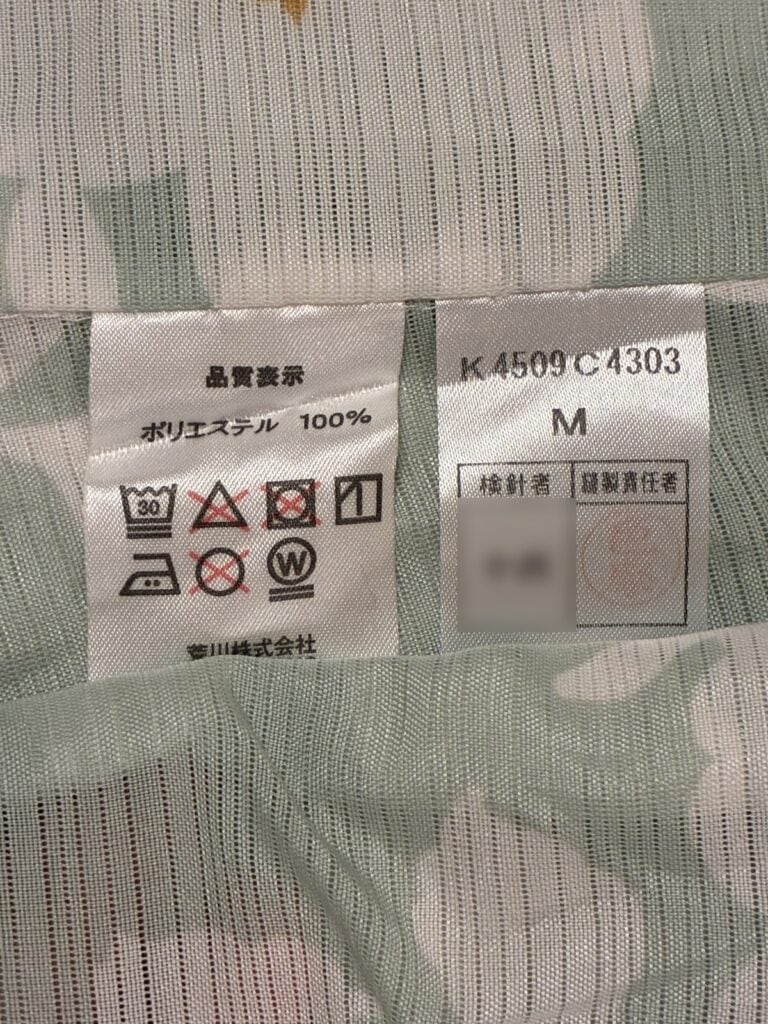 ポリエステル100%と洗濯機のマークが記載された品質表示のタグ