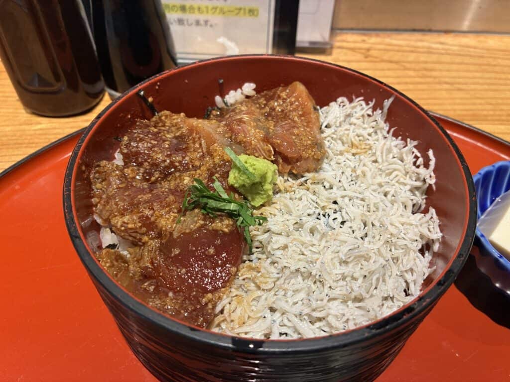 漬けマグロとしらすがのった丼のアップ。白い胡麻がたっぷりまぶされている