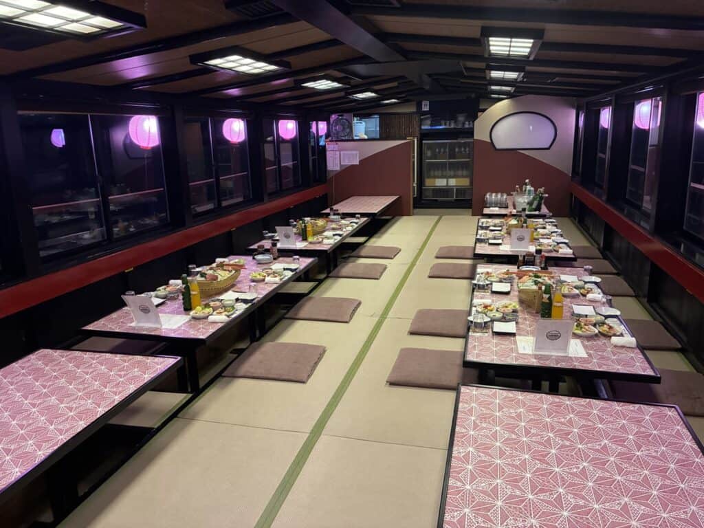 屋形船の船内。掘り炬燵式の長いテーブルが両側に並んでいる