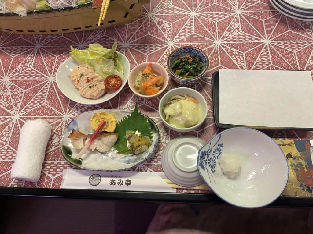 屋形船の前菜の膳。小鉢がいくつも並び、手前に「屋形船 あみ幸」の箸袋がある