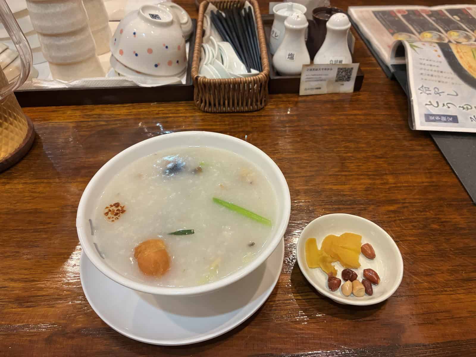 白い器に入ったとろとろの香港粥と、お漬物と落花生の小皿