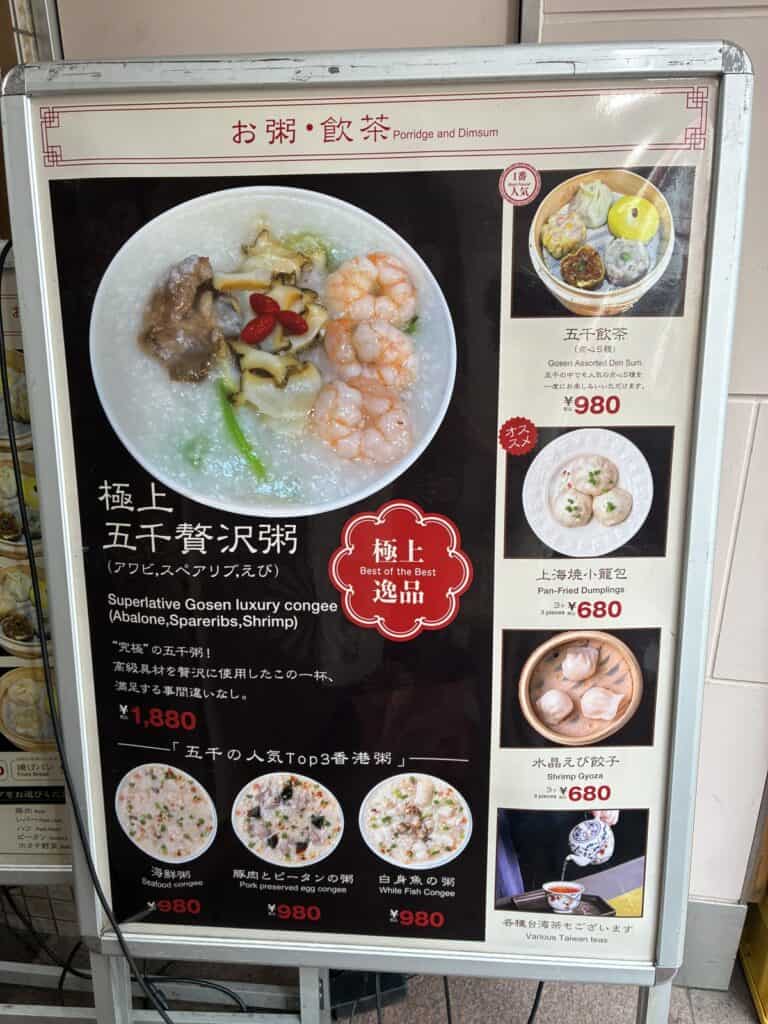 五千の店頭メニュー看板。香港粥と点心の写真と値段が並んでいる