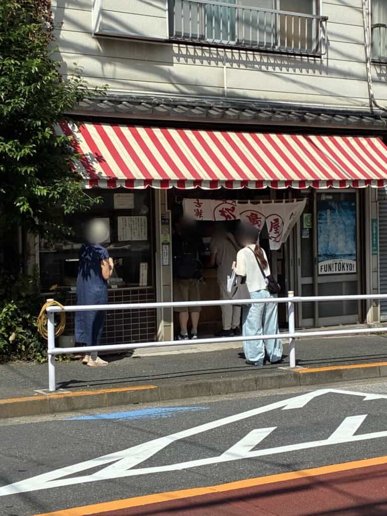 赤と白のしま模様の日除けと、松島屋の暖簾が下がった店先