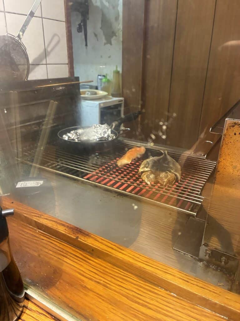 網で魚を焼いているところ。カウンターの目の前に焼き台がある