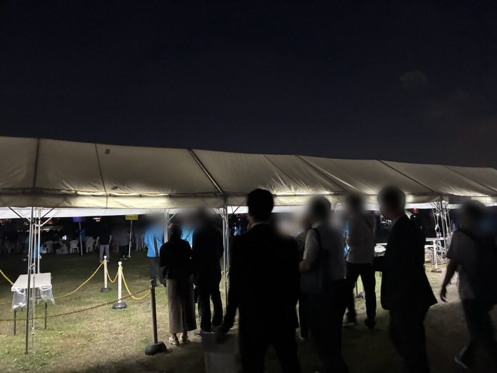 有料観覧席の入り口になっている白いテント。夜の暗い中、人が並んで入場を待っている