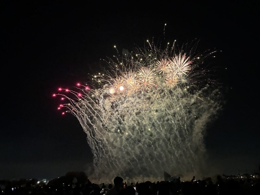 夜空いっぱいに広がる金色の花火と、地上から噴き上がる仕掛け花火